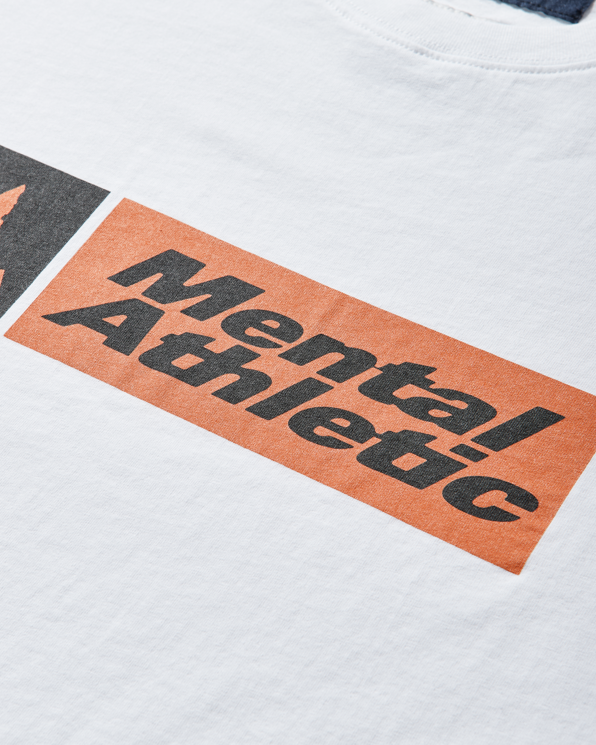 Close-up of the orange and black ROA x Mental Athletic logo printed on the front of the T-shirt.