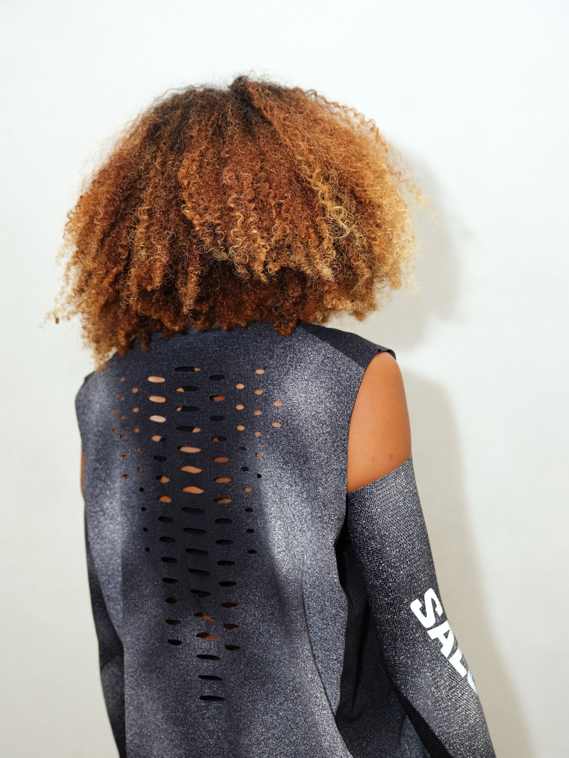 Close-up side detail of model wearing BACKBONE TANK U MENTAL ATHLETIC, breathable performance fabric with Salomon branding.