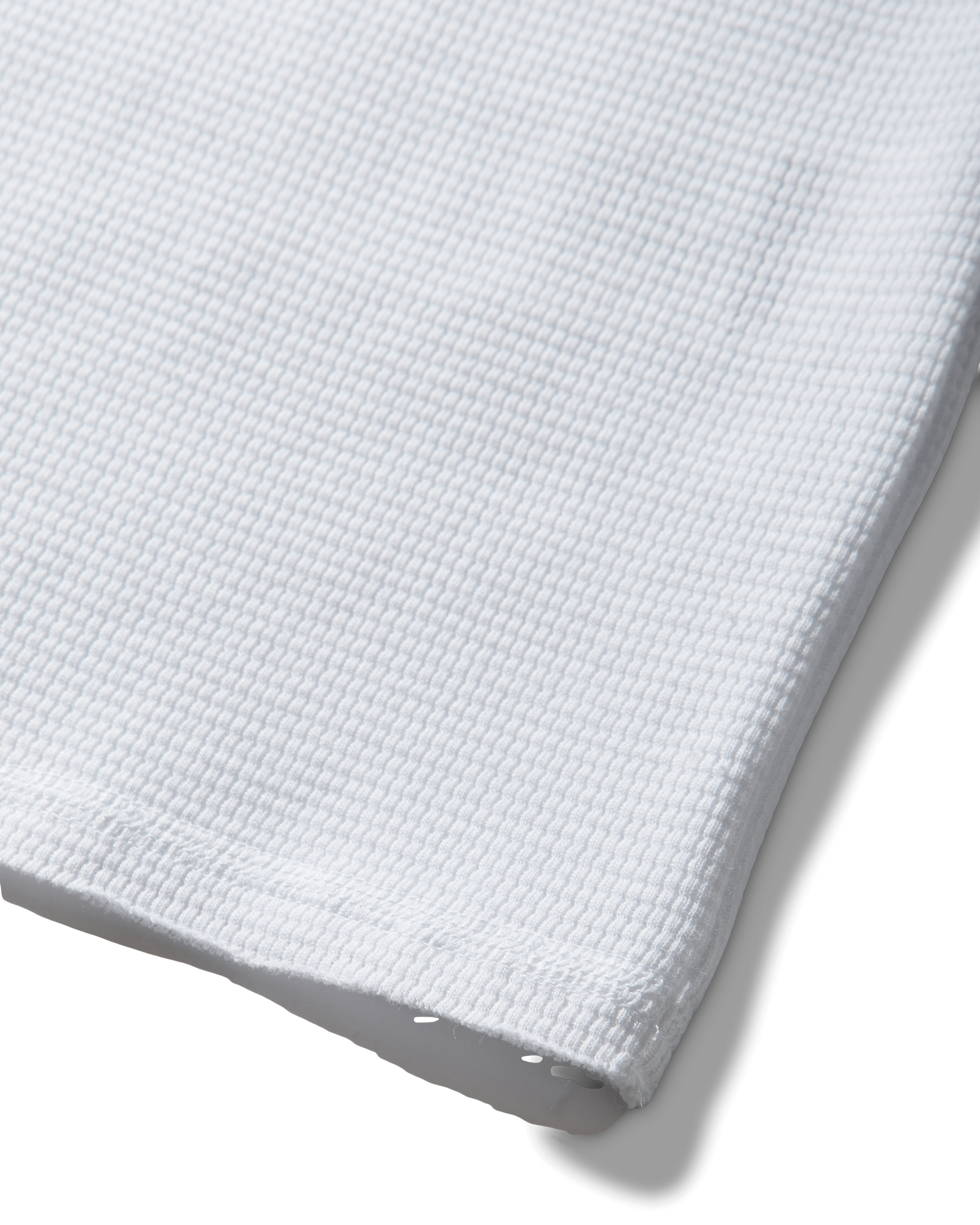 Mental Athletic white cotton tank top detail of raw-cut hem and textured fabric.