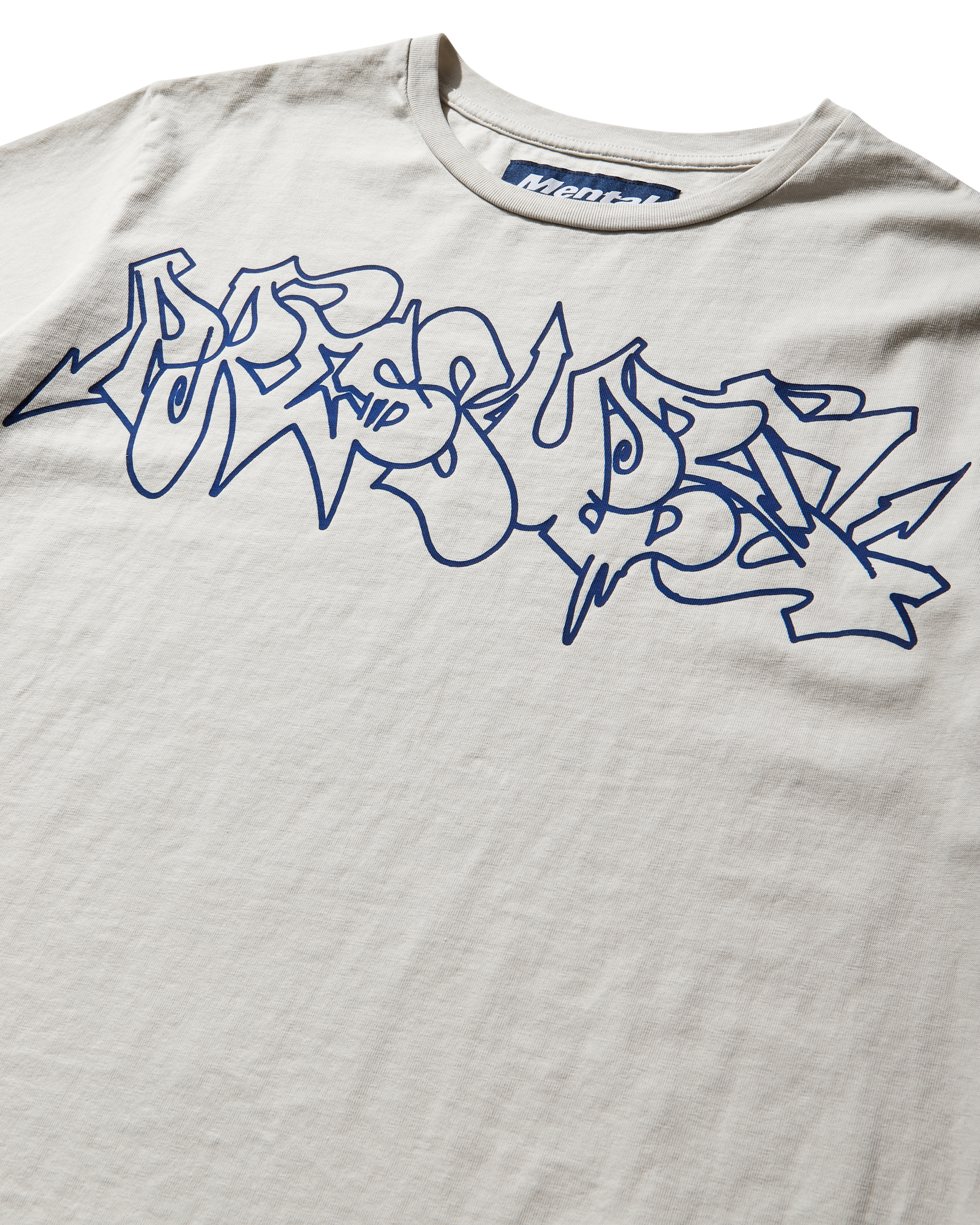 Mental Athletic x Pressure off-white t-shirt detail of graffiti-style logo print on chest.