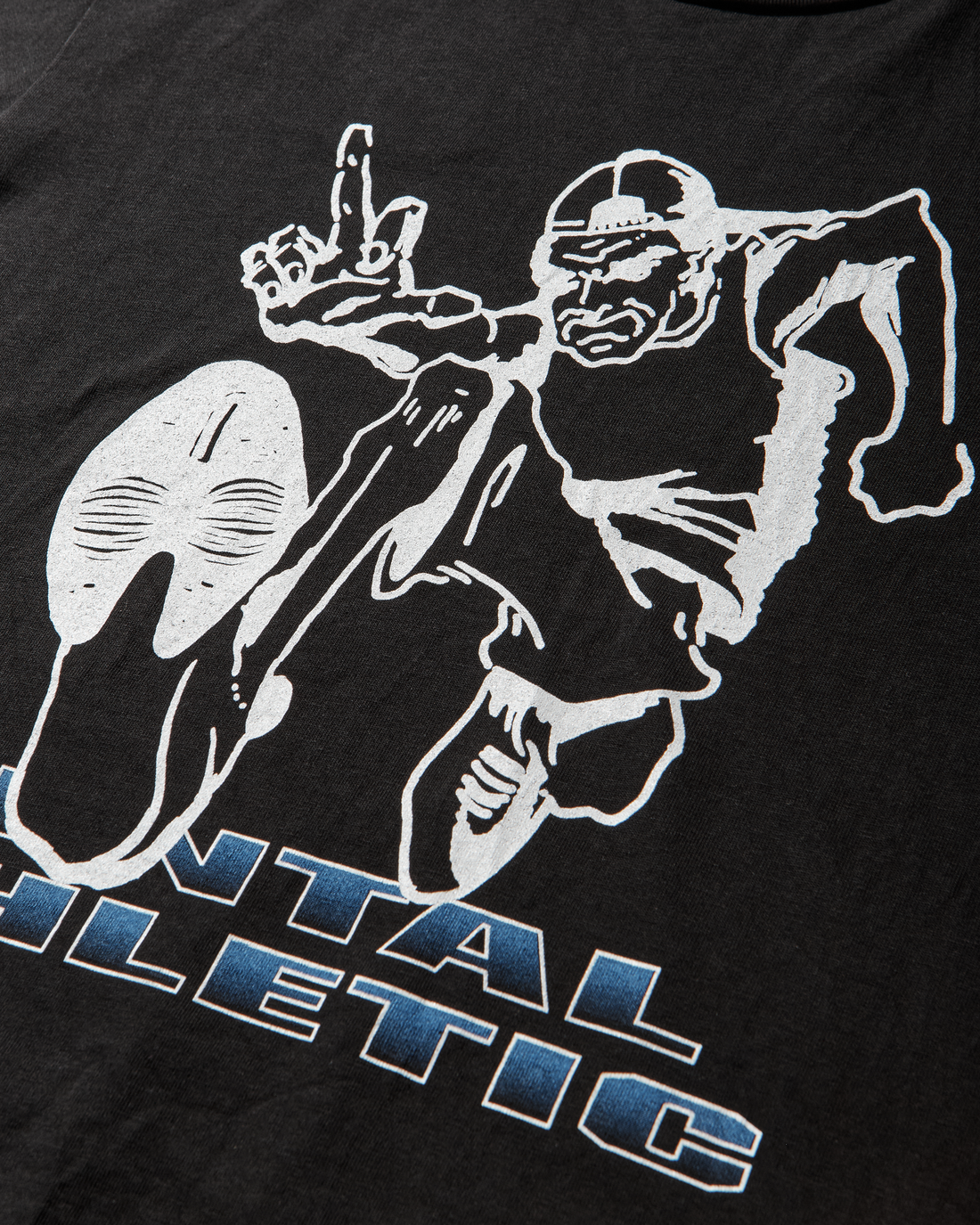 Mental Athletic “Tokyo Calling” black t-shirt close-up of running character graphic with blue lettering.