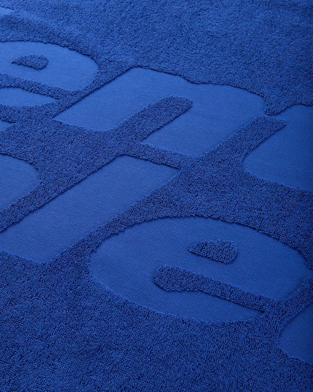 Close-up of the blue terry fabric showing the raised tone-on-tone Mental Athletic logo.