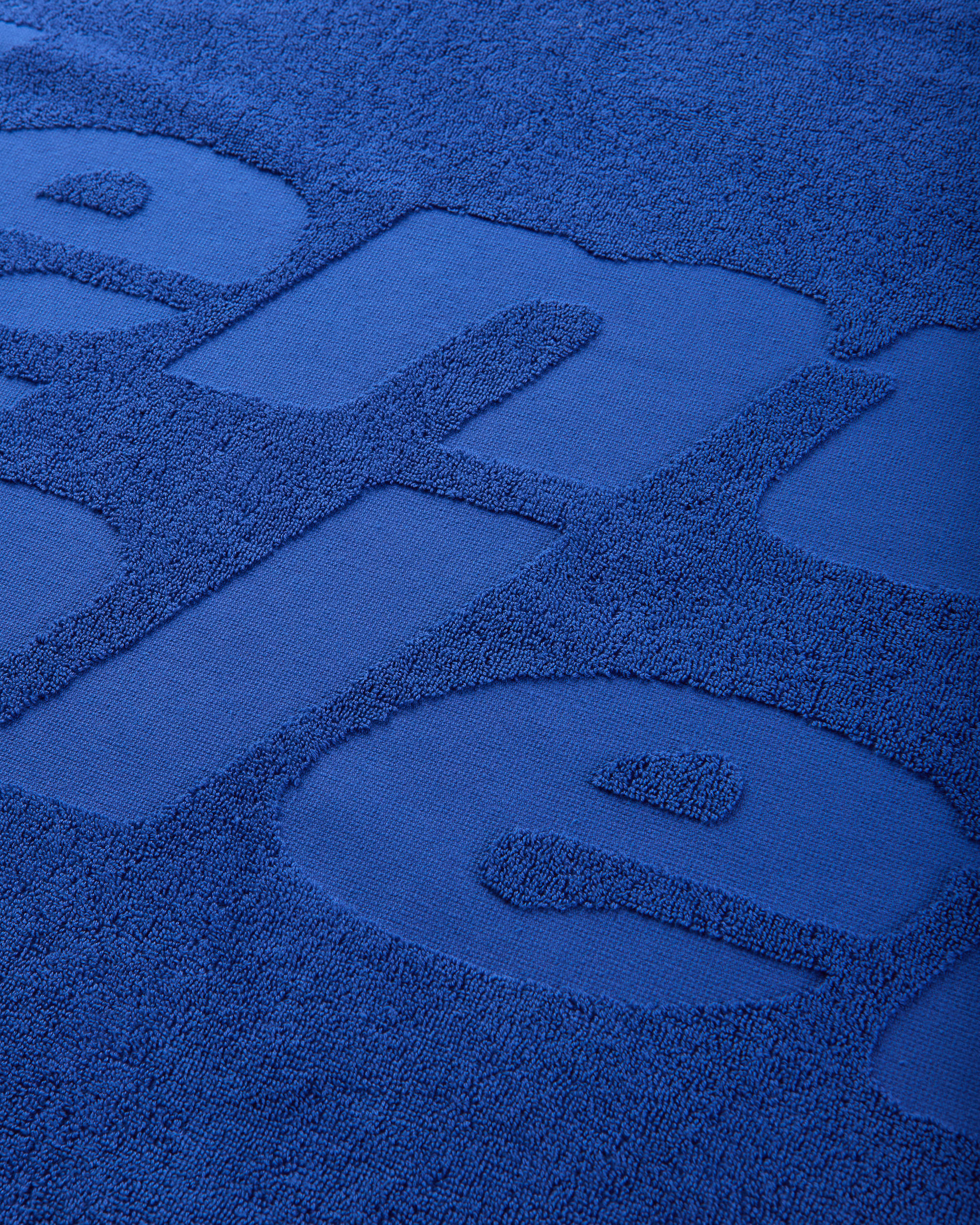 Close-up of the blue terry fabric showing the raised tone-on-tone Mental Athletic logo.