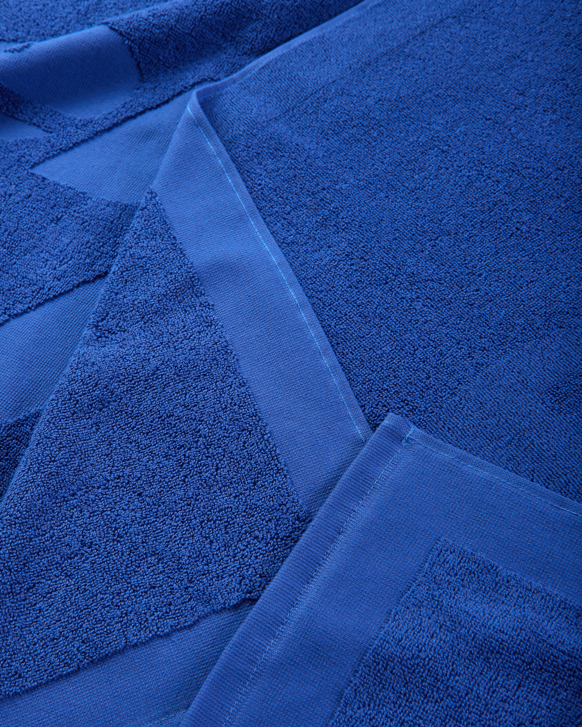 Close-up of the towel’s edge, stitching, and hanging loop in matching blue fabric.