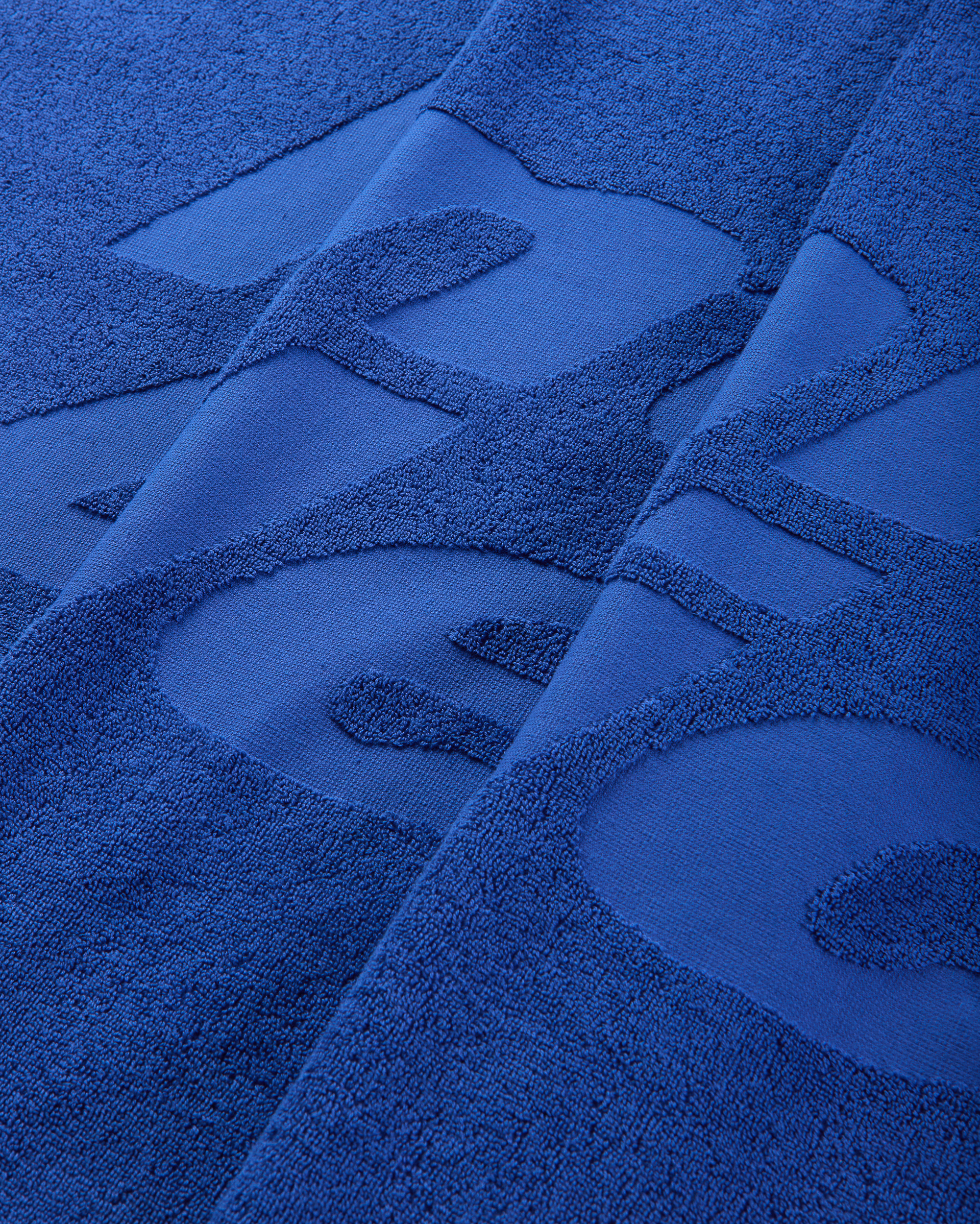 Detailed close-up of the jacquard lettering woven into the blue cotton towel.
