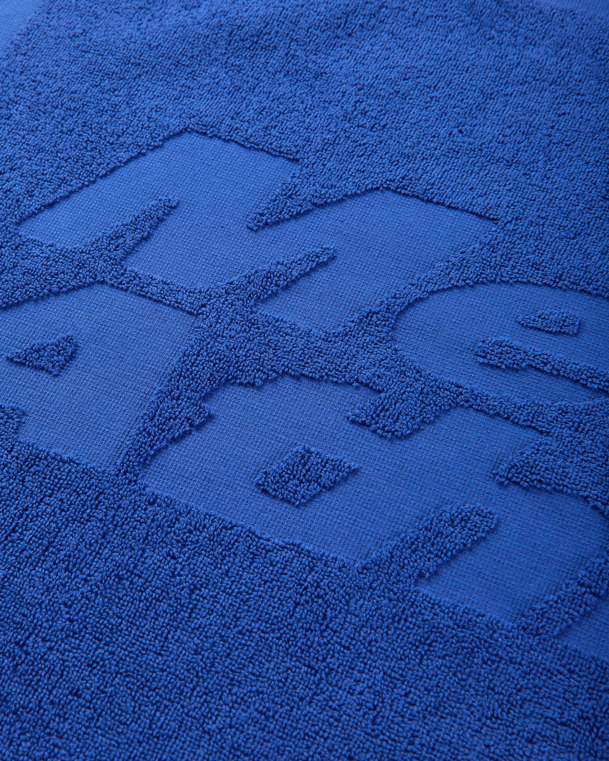 Close-up of the blue terry fabric showing the raised tone-on-tone Mental Athletic lettering.