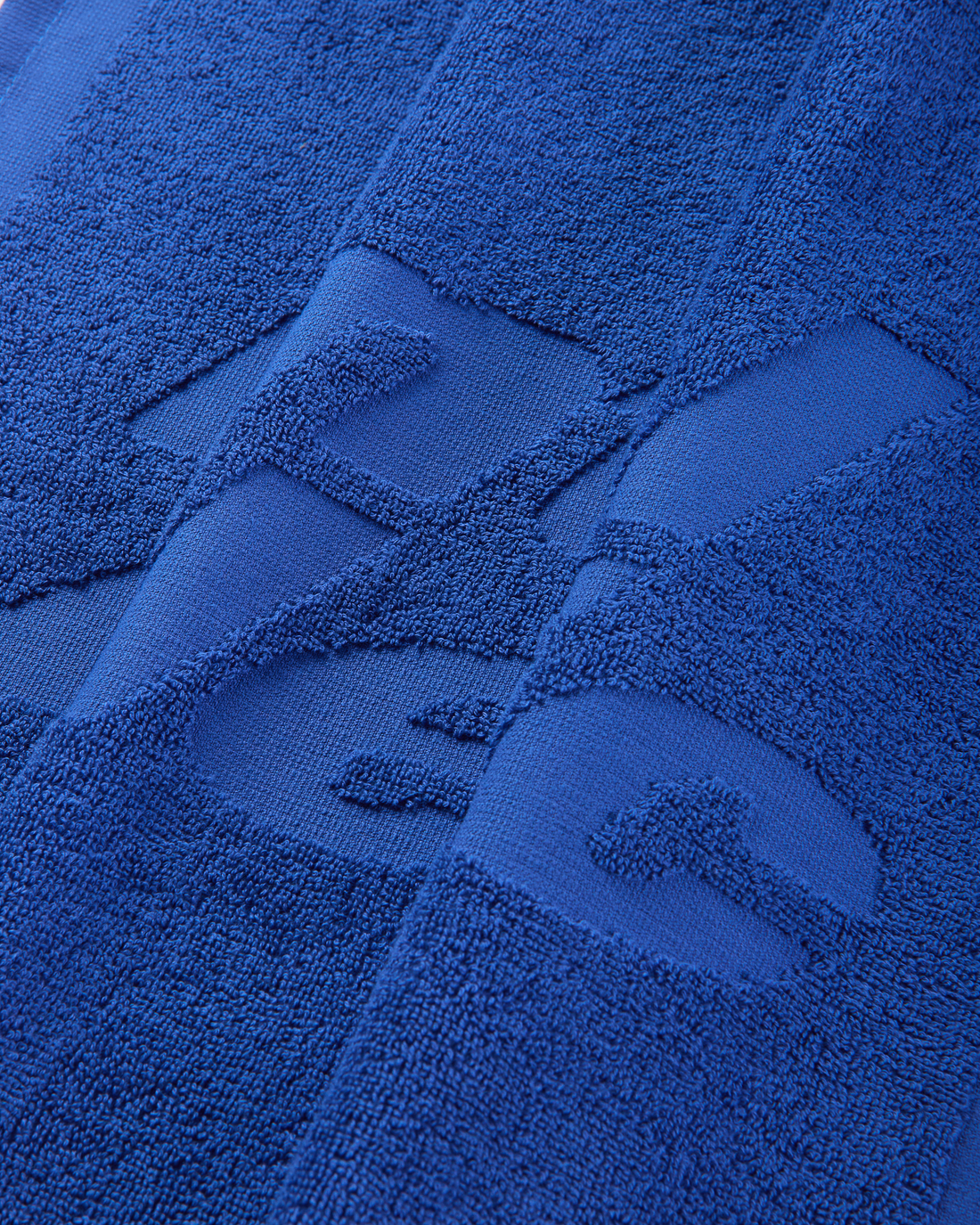 Close-up of the tonal Mental Athletic logo woven into the blue cotton towel.
