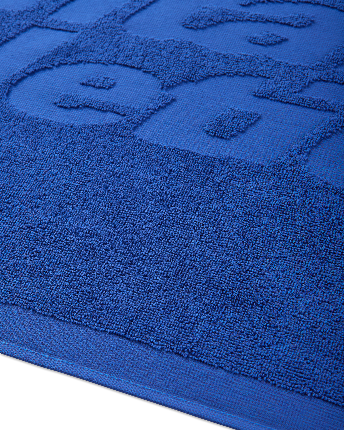 Detailed close-up of the small towel’s jacquard logo and finished edge.